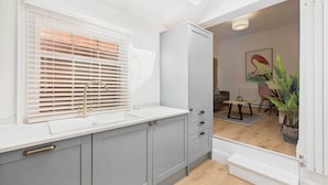Una cocina moderna con ventanal, pileta y alacena.