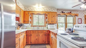 A kitchen with wooden cabinets, a stainless steel refrigerator, a microwave, and a stove. - Private Dock, Deck & Yard: Deerskin Lake Retreat! (Eagle River)