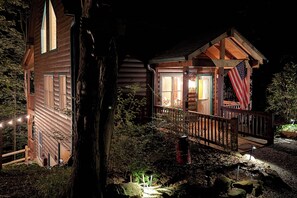 Une cabane avec une façade en bois, un porche et une petite terrasse.