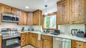 Una cocina con armarios de madera, electrodomésticos de acero inoxidable y un ventanal que proporciona luz natural.