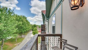Ein Balkon mit Holzbank, Geländer und Blick auf eine Straße und Bäume.