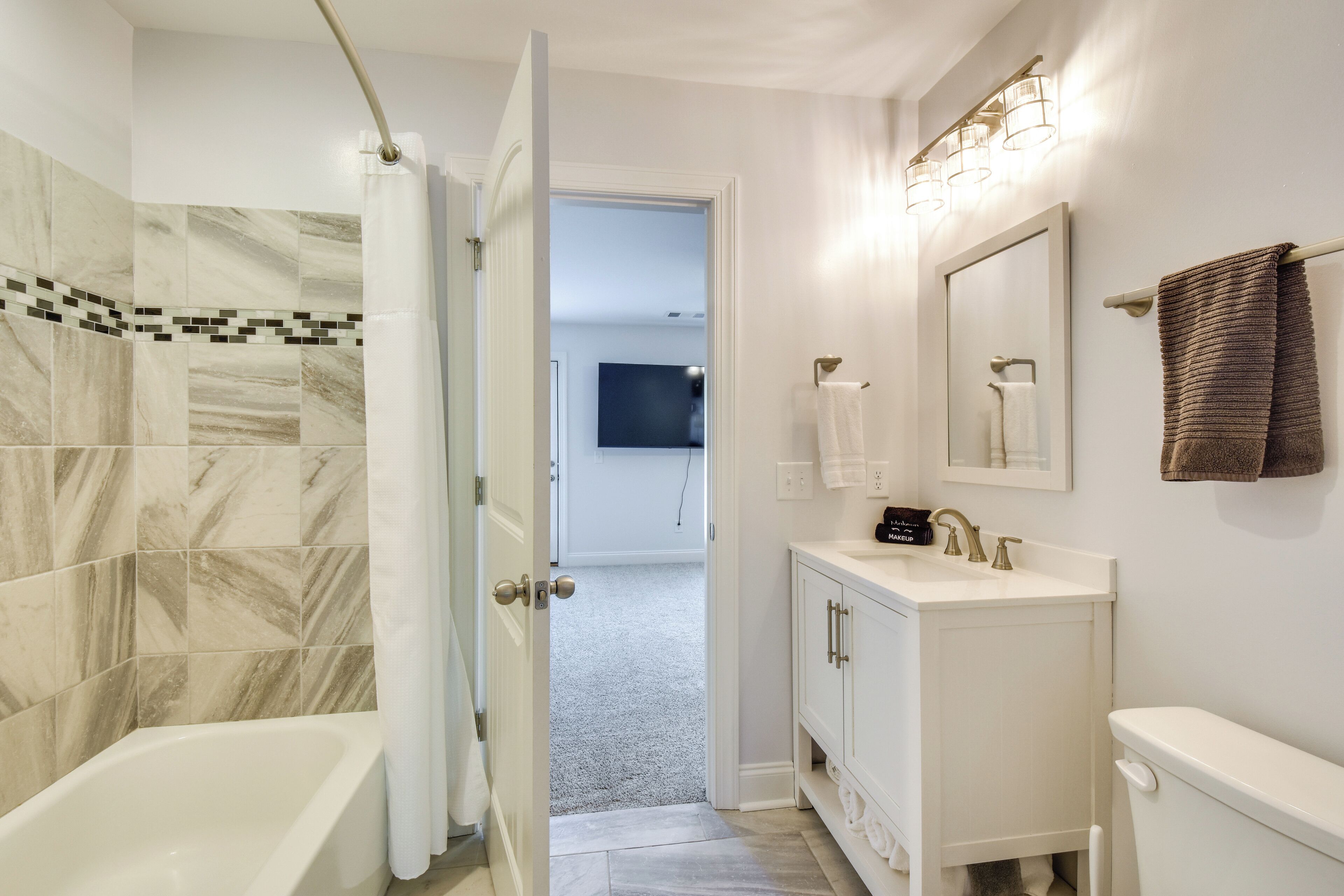 A modern bathroom with a bathtub, white vanity, and a shower curtain.