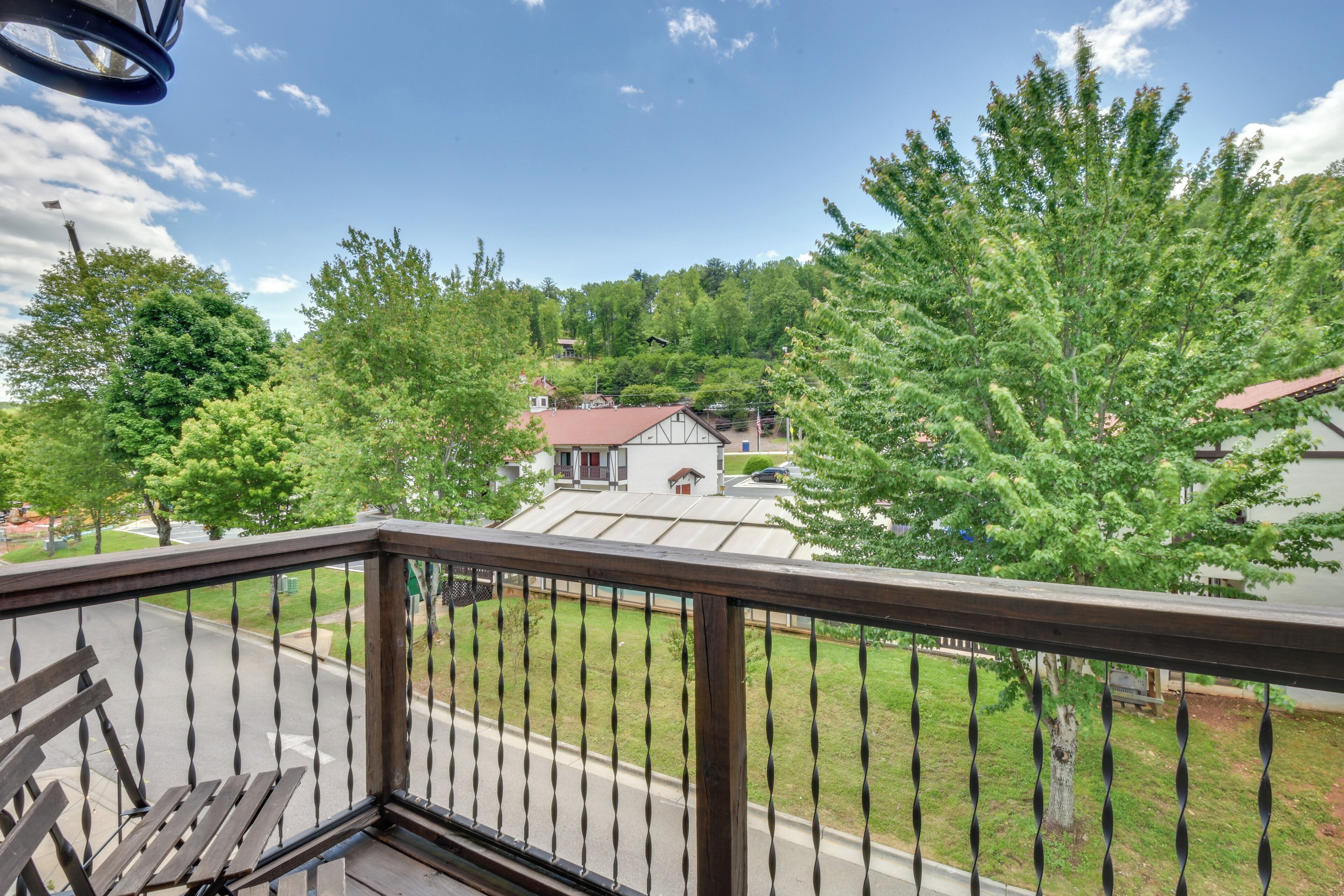 A balcony with a view of a residential area, including houses and trees.