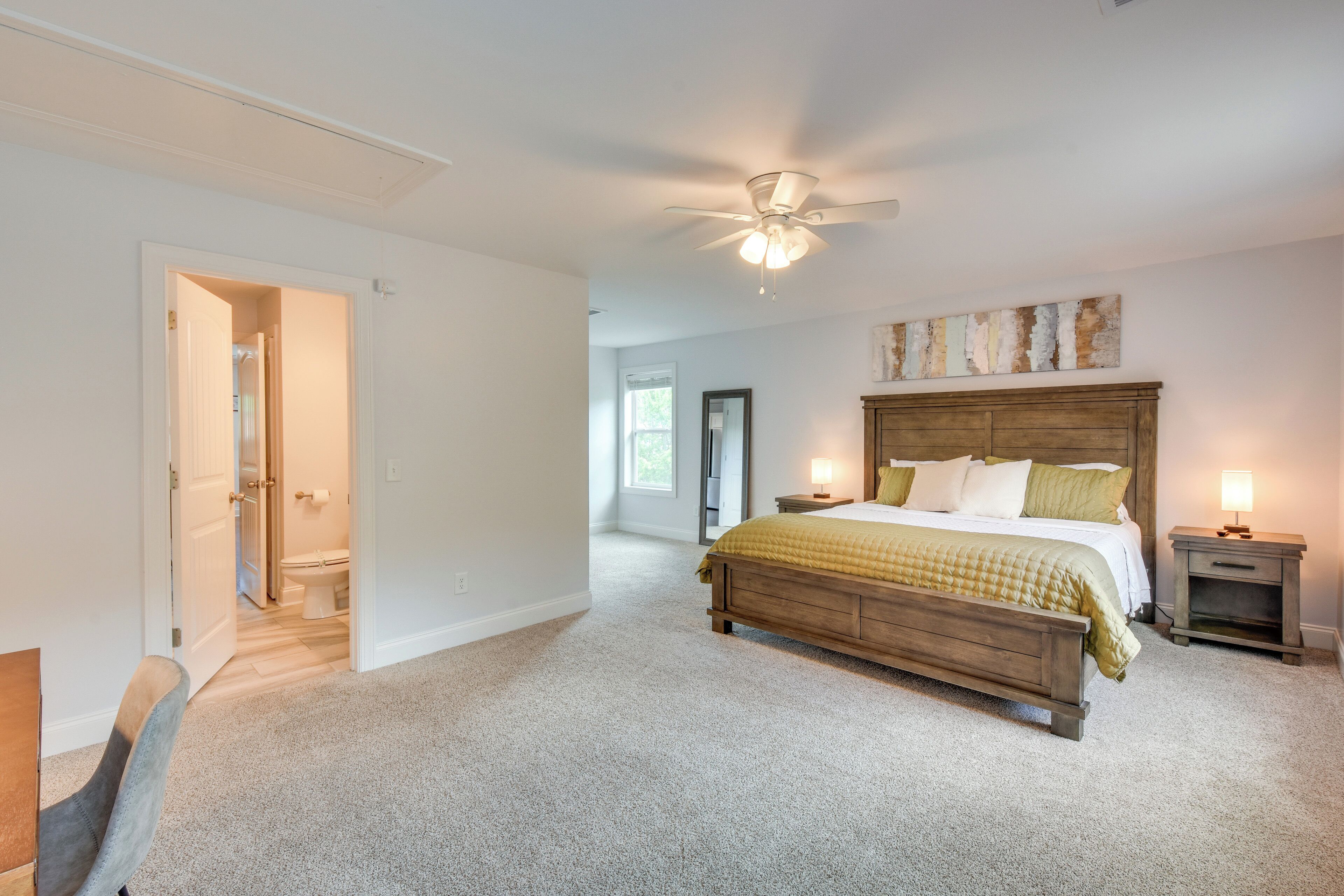 A bedroom with a wooden bed, a ceiling fan, and a nightstand with a lamp.