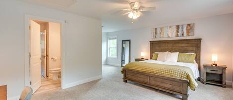 A bedroom with a wooden bed, a ceiling fan, and a nightstand with a lamp.