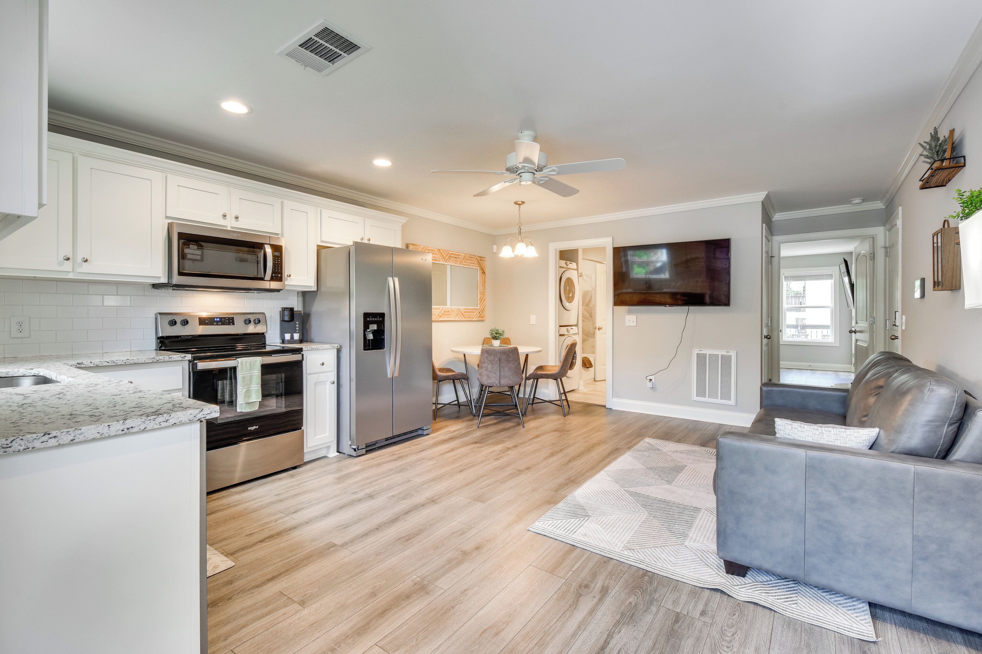 A modern kitchen with white cabinets, stainless steel appliances, and a dining area with a table and chairs.