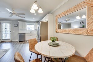 Une cuisine moderne avec des armoires blanches, un îlot en marbre et un ventilateur de plafond.
