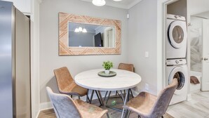Een moderne keuken met een ingebouwde oven, een eettafel met stoelen en een grote spiegel erboven.
