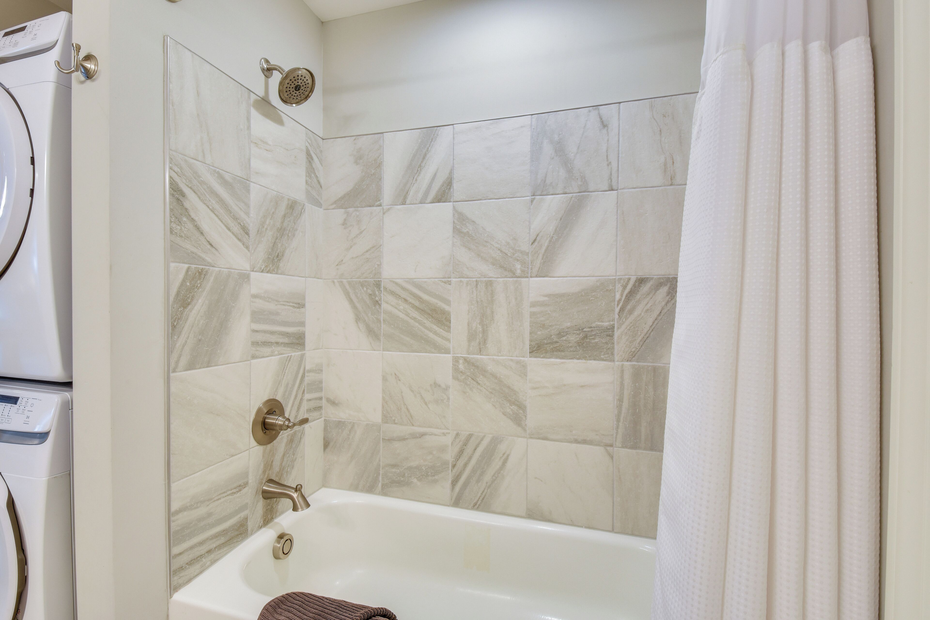 Une salle de bain avec une baignoire blanche, une douche équipée d’un pommeau de douche amovible et des toilettes.