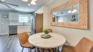 Eine moderne Küche mit weißen Schränken, einem Edelstahlkühlschrank und einem Essbereich mit einem Marmortisch und Ledersesseln.