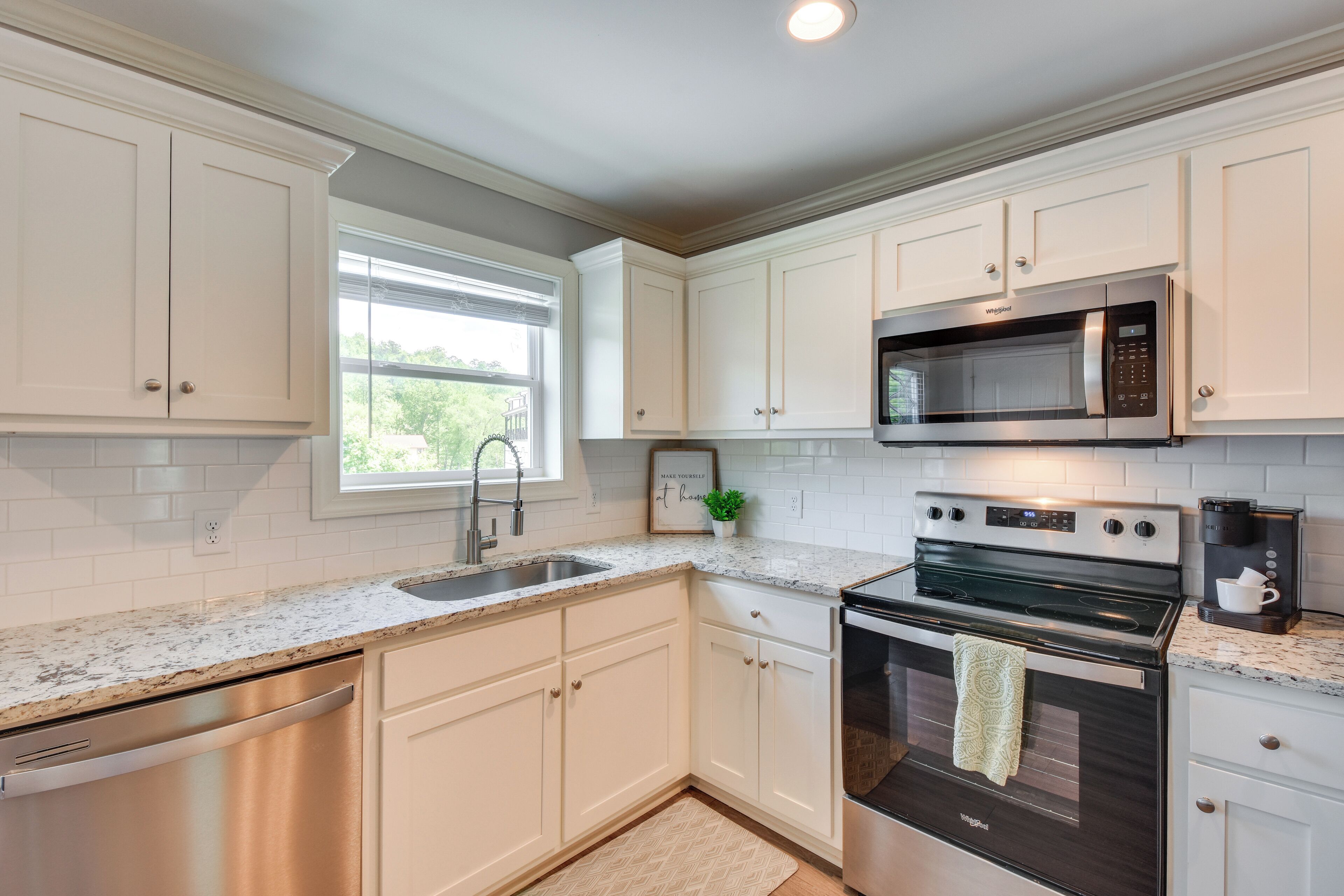 A modern kitchen with white cabinetry, stainless steel appliances, and a granite countertop.
