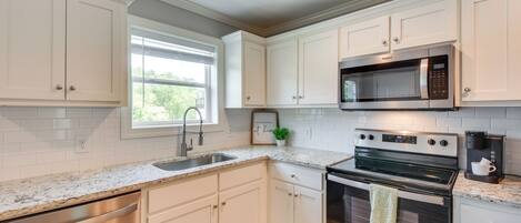 A modern kitchen with white cabinetry, stainless steel appliances, and a granite countertop.