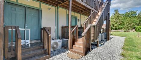 A two-story building with a wooden balcony, a staircase, and a gravel driveway.