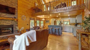 A spacious log cabin interior with a living area, kitchen, and a loft bedroom. - Family Friendly: Hot Tub Haven in Mineral Bluff! (Mineral Bluff)