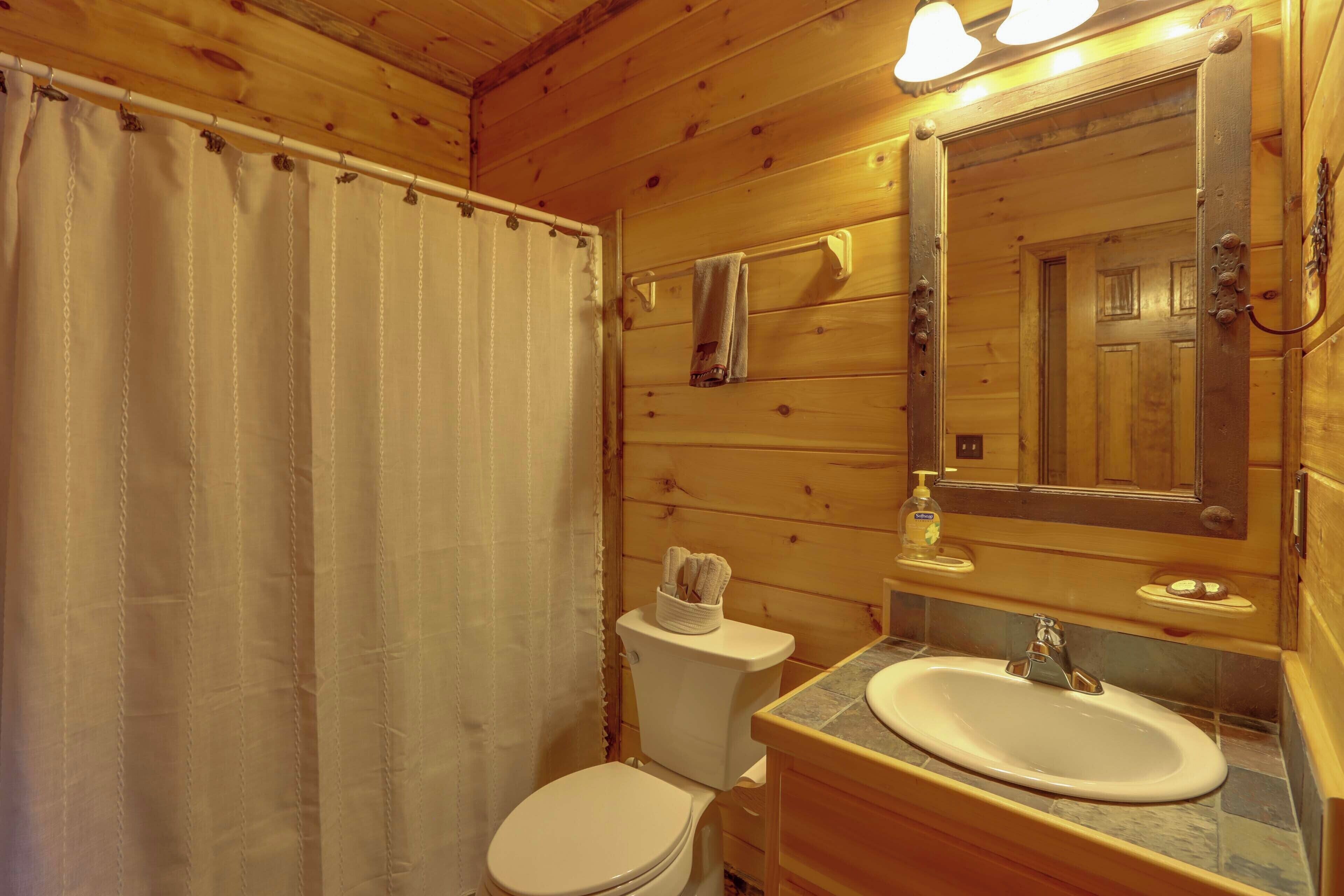 A wooden cabin bathroom with a toilet, sink, and mirror.