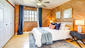 Une chambre avec un plafond en bois, un lit avec une literie blanche, une table de chevet et une fenêtre avec des rideaux.