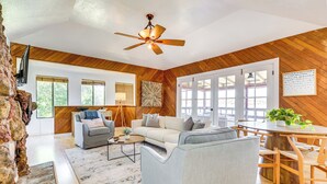 Un vaste espace de vie doté d’un plafond en bois, d’un ventilateur de plafond, d’un canapé, d’une table basse et d’une table à manger avec des chaises.