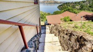 Un escalier menant à une maison d’où l’on a vue sur un lac et des collines.