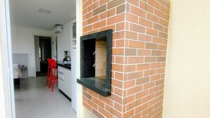 Une cuisine avec un mur en briques, un plan de travail noir et une chaise rouge.