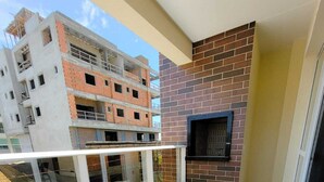 Un balcon doté d’une balustrade en verre, d’un mur en briques et d’une fenêtre.