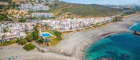 A coastal residential area with a large hotel complex, a beach, and clear blue waters.