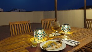 A wooden dining table set for two with a plate of food, a glass of wine, and a decorative lantern. - Penthouse with sea and mountain views on the Costa del Sol. (Manilva)