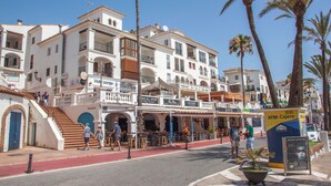 A coastal building with balconies, a red pedestrian path, and palm trees. - Penthouse with sea and mountain views on the Costa del Sol. (Manilva)