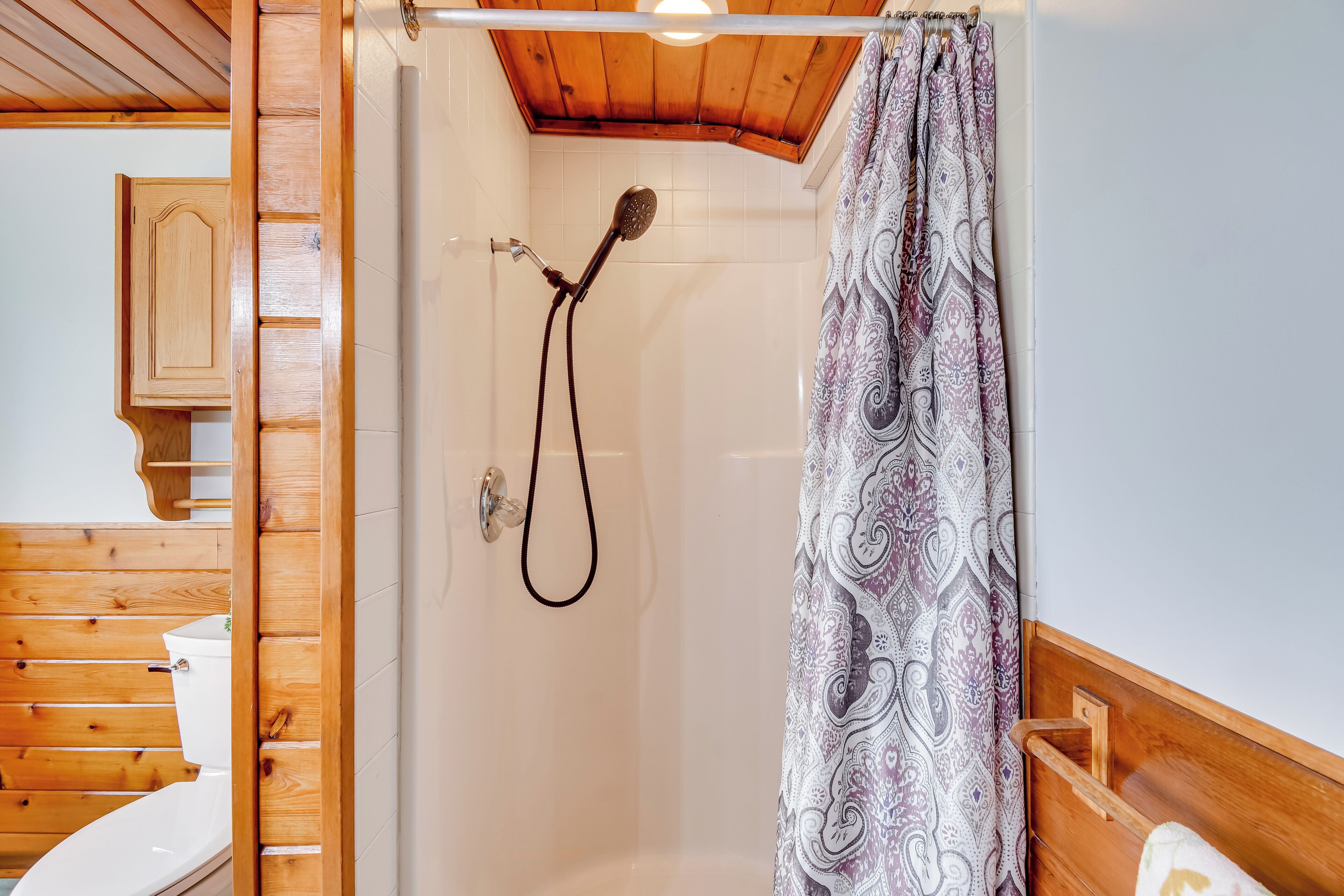 Ein Badezimmer aus Holz mit Dusche, Toilette und einem Holzschrank.