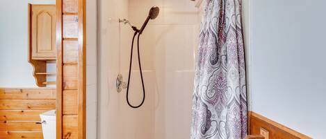 Ein Badezimmer aus Holz mit Dusche, Toilette und einem Holzschrank.