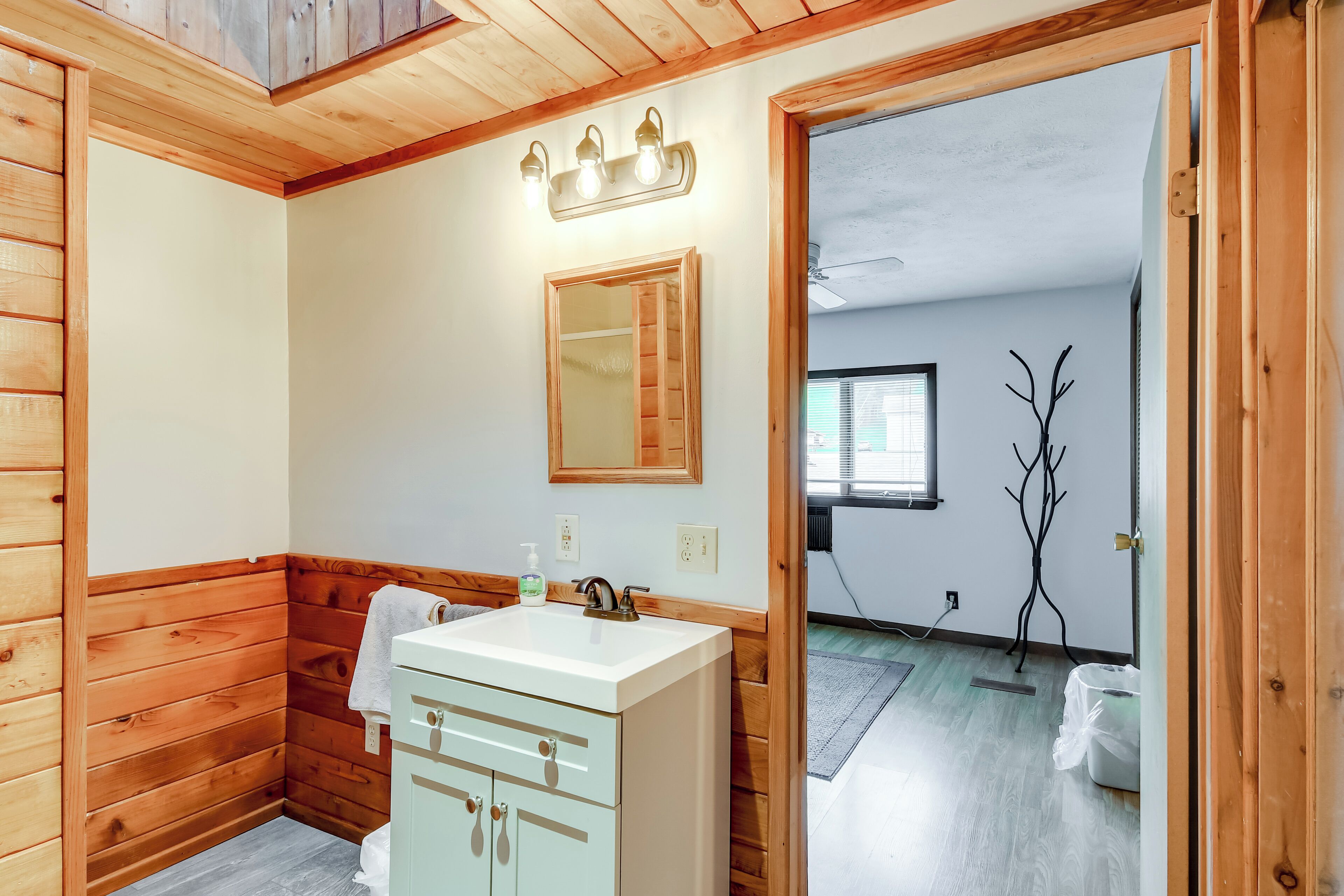 A wooden-paneled bathroom with a white sink, mirror, and wooden cabinet.