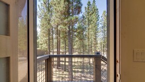 A balcony with a metal railing overlooking a forested area. - Fish, Boat & Hike: Modern Portola Studio (Portola)