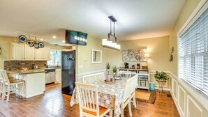 A spacious kitchen with wooden flooring, a central island, and a dining area with white chairs. - 3 Mi to Erie Canal: Home w/ Hot Tub in Holley! (Holley)