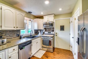 Uma cozinha moderna com armários brancos, eletrodomésticos de aço inoxidável e bancada de granito.