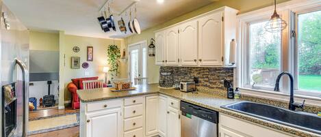 A modern kitchen with white cabinets, granite countertops, and stainless steel appliances.