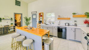 Una cocina moderna con una isla central, taburetes de bar, lavavajillas y fregadero.