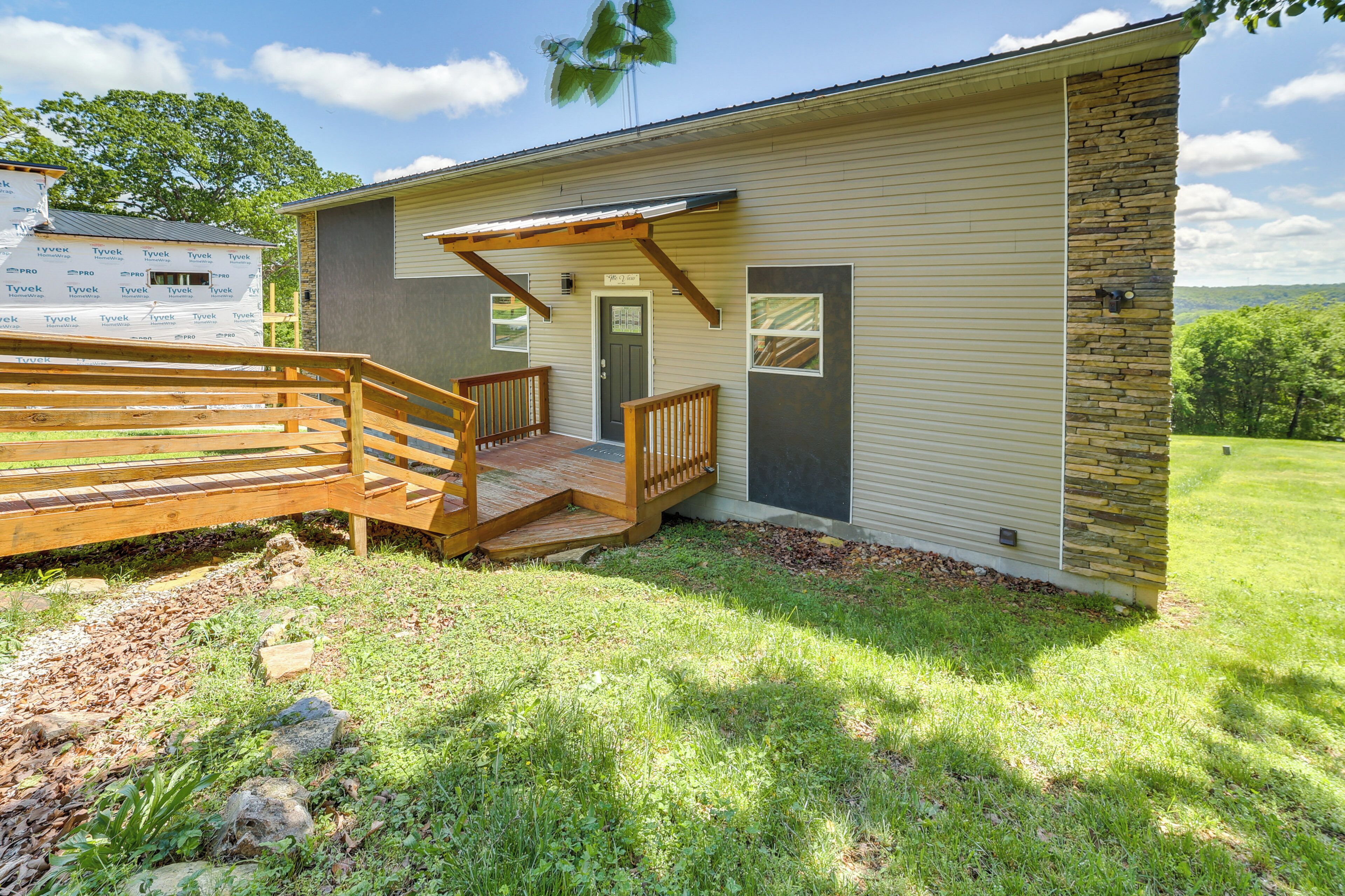 A single-story house with a covered porch and a wooden staircase leading to a door.