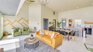 Un espacio habitable amplio con un sofá amarillo, una mesa de comedor y una cocina con barra.