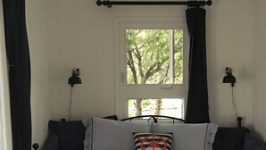 A bed with striped bedding, a window with curtains, and two wall-mounted lamps.