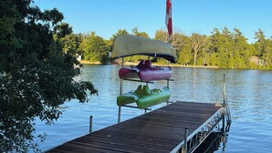 A wooden dock extending into calm water, with a rowboat and a canoe docked on it.