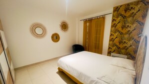 Une chambre à coucher comprenant un lit, une chaise, un rideau et deux éléments de décoration murale.
