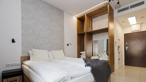 A modern bedroom with a large bed, wooden headboard, built-in wardrobe, and bedside lamps.