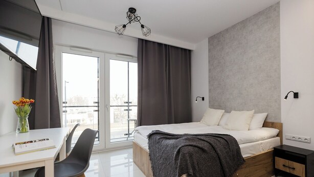A modern bedroom with a large bed, a desk, and a chair.