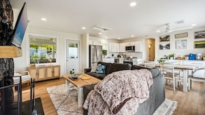 A modern living room with a grey sofa, wooden coffee table, and a TV mounted on a wall. - Lakefront Cabin Hot Tub, Dock, and Adventure Shed (Sturgeon Bay)