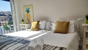 Una camera d'albergo con un letto, cuscini, una coperta, un quadro e vista sugli edifici.