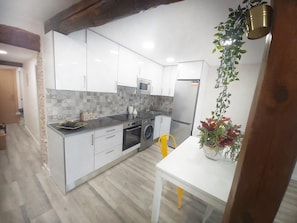 A modern kitchen with white cabinets, a stainless steel refrigerator, and a washing machine.