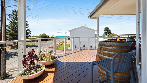 Une terrasse en bois avec des sièges d’extérieur, un tonneau et des plantes en pot.