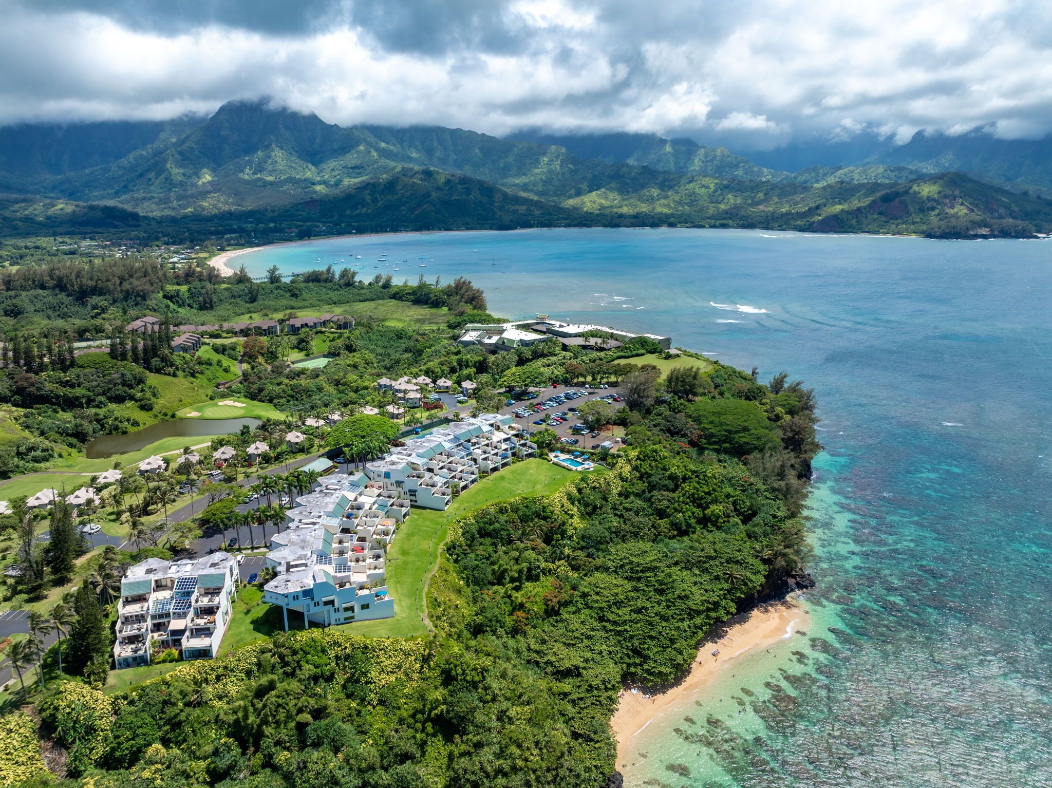 An aerial view of a resort with multiple buildings, a golf course, and a beach.