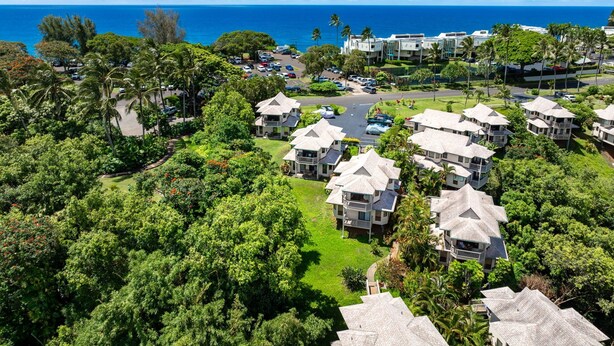 Ein Küstenresort mit mehreren bungalowartigen Gebäuden, einem Parkplatz und üppiger Vegetation.