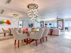 A modern dining area with a round table, chairs, and a chandelier. - Oceanfront 3BR | Pools, Spa, Gym & Restaurants (Puerto Vallarta)
