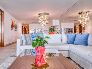 A modern living room with a sectional sofa, a wooden coffee table, and a large mirror reflecting the room. - Oceanfront 3BR | Pools, Spa, Gym & Restaurants (Puerto Vallarta)